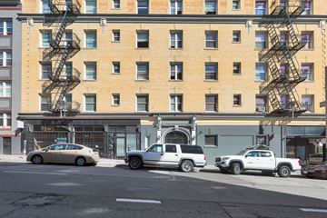 San Francisco apartment for rent - A tan car is parked in front of a building with a fire escape.