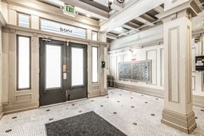 San Francisco apartment for rent - A hallway with a black and white checkered floor, a black door, and a white wall with a calendar on it.