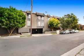 Los Angeles apartment for rent - A street view of a residential area with apartment buildings and parked cars.