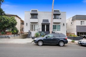 West Hollywood apartment for rent - A black SUV is parked in front of a white two-story house.