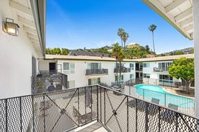 Los Angeles apartment for rent - A balcony with a pool and palm trees in the background.