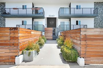 Los Angeles apartment for rent - A modern building with a black door and windows, surrounded by wooden fences and plants.