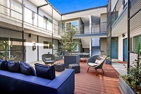 Los Angeles apartment for rent - A blue couch is on a wooden deck in front of a building.