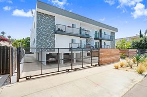 Los Angeles apartment for rent - A modern two-story house with a white and grey exterior and a black metal fence.