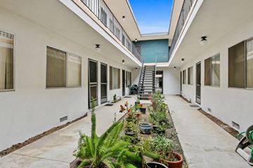 Los Angeles apartment for rent - A long white building with a balcony and plants on the ground.
