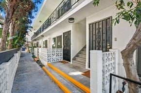 Los Angeles apartment for rent - A white building with a black gate and a yellow line on the sidewalk.