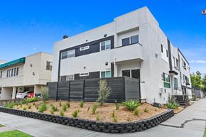 Los Angeles apartment for rent - A modern white building with a black fence and a green roof.