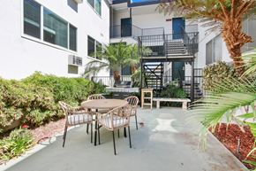 Hollywood apartment for rent - A patio with a table and chairs is surrounded by green plants.