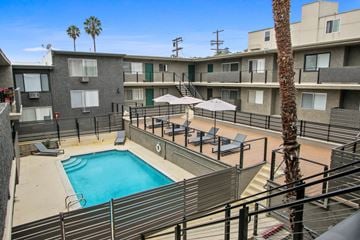 Los Angeles apartment for rent - A pool surrounded by apartment buildings and palm trees.