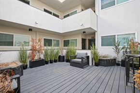 Los Angeles apartment for rent - A balcony with a grey bench and black planters.