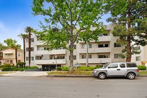 Los Angeles apartment for rent - A silver car is parked in front of a white apartment building.