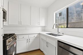 Santa Monica apartment for rent - A kitchen with white cabinets and a black stove top oven.