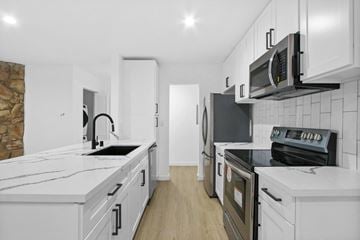 Mar Vista apartment for rent - a kitchen with white cabinets and black appliances and white counter tops