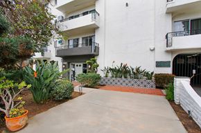 Los Angeles apartment for rent - A white building with a balcony and a small garden in front.