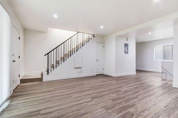Los Angeles apartment for rent - A spacious room with wooden flooring and a staircase with a metal railing.