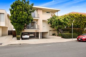 Los Angeles apartment for rent - A white two-story apartment building with a red car parked in front.