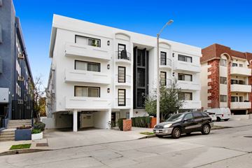 Los Angeles apartment for rent - A modern white apartment building with a black car parked in front.