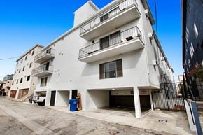 Los Angeles apartment for rent - A white building with balconies and a blue trash bin in front.