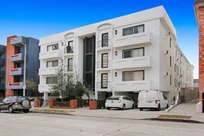 Los Angeles apartment for rent - A white apartment building with cars parked in front.