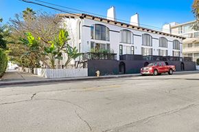 Marina Del Rey apartment for rent - A red car is parked on the side of a street in front of a white building.