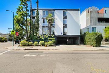 Los Angeles apartment for rent - A street view of a building with a stop sign and a tree.