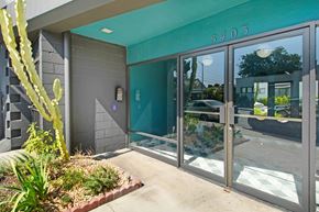 Los Angeles apartment for rent - The image shows the entrance to a building with glass doors and a cactus plant in front.