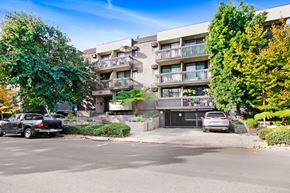 West Hollywood apartment for rent - A black car is parked on the left side of a street in front of a building with a balcony.
