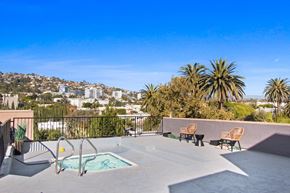 West Hollywood apartment for rent - A pool area with chairs and a view of a city in the background.