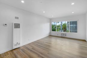 Los Angeles apartment for rent - A spacious room with wooden flooring and a window overlooking a green landscape.