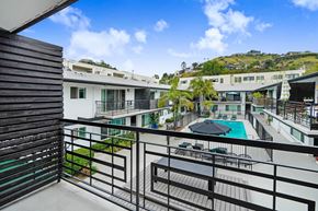 Los Angeles apartment for rent - A balcony with a pool and a view of a hillside with houses.