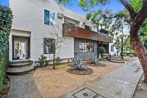 West Hollywood apartment for rent - A white house with a brown roof and a tree in front.