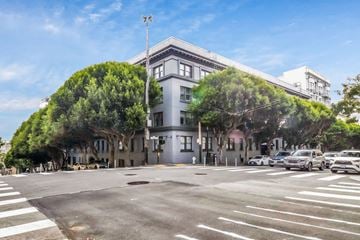 San Francisco apartment for rent - A street view with cars and a building with a green tree on the side.