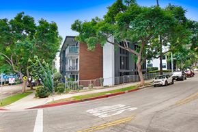 West Hollywood apartment for rent - A street view with a car driving on the road and a building on the side.