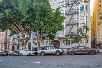 San Francisco apartment for rent - Cars parked on a street in front of a building with a tree.