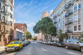 San Francisco apartment for rent - A tree in the middle of a street lined with parked cars.