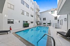 West Hollywood apartment for rent - A swimming pool in a courtyard surrounded by white buildings.