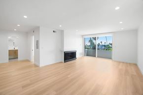 Santa Monica apartment for rent - A spacious room with wooden flooring and a large window overlooking a beach.