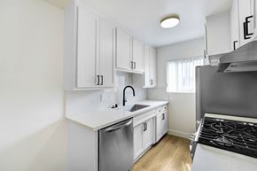 Venice apartment for rent - A kitchen with white cabinets and a stainless steel sink and stove.