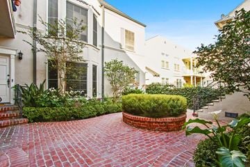 Beverly Hills apartment for rent - A red brick pathway leads to a white building with a black door.