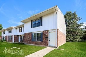 Huber Heights townhouse for rent - A white house with a brick wall and a sign that says Vinebrook Homes.
