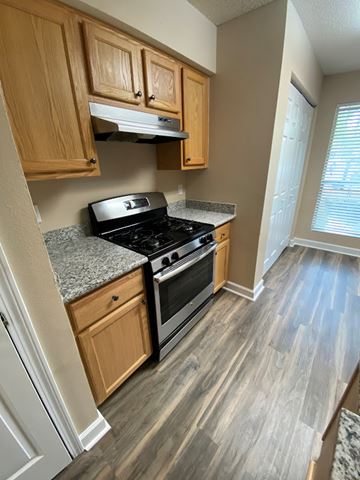 Pensacola house for rent - A kitchen with wooden cabinets and a black stove top oven.