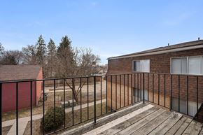 Dekalb apartment for rent - a balcony with a wooden deck and a brick building