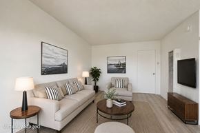 Van Nuys apartment for rent - A living room with a white couch, a coffee table, and a television.