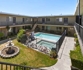 Van Nuys apartment for rent - A pool surrounded by a fence and a bicycle.