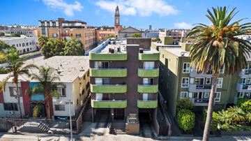 Los Angeles apartment for rent - A tall green building with a balcony in the middle stands in front of a red building.