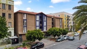 Los Angeles apartment for rent - A view of a street with cars and apartment buildings.
