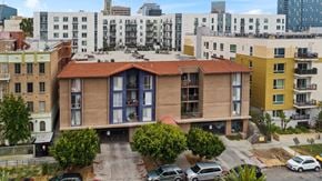 Los Angeles apartment for rent - A building with a red tile roof is surrounded by other buildings and has cars parked in front.