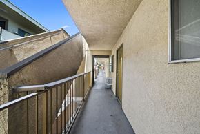 Los Angeles apartment for rent - A long, narrow hallway with a metal railing on the left side and a wall on the right side.