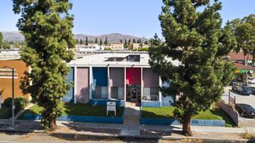 North Hills apartment for rent - A building with a blue and pink facade is surrounded by trees.
