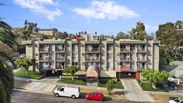 Los Angeles apartment for rent - A red car is parked in front of a white van.